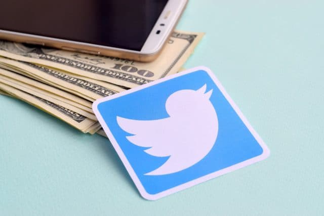 Twitter logo next to dollars and smartphone