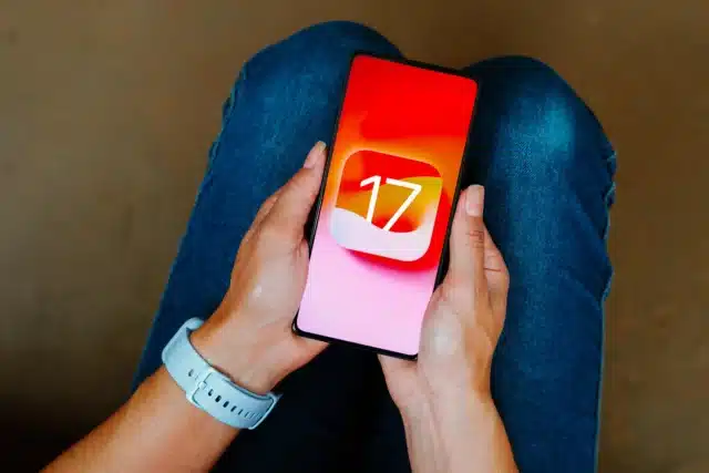 Woman holding iPhone with iOS 17 logo